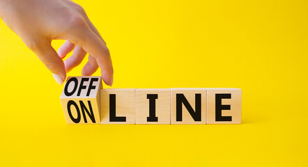 Offline and online symbol. Businessman hand turnes wooden cubes and changes word Online to Offline. Beautiful yellow background. Business concept. Copy space.