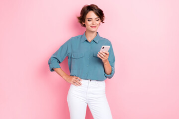 Fototapeta Portrait of positive lovely girl with bob hairdo wear blue blouse read notification message comment isolated on pink color background obraz