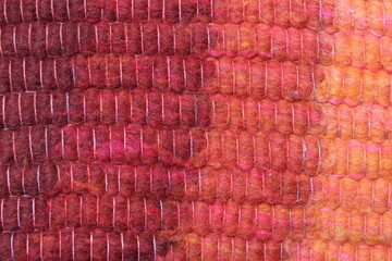 Closeup of red wool yarn cloth abstract background. Surface of fabric texture in red, crimson, reddish yellow and orange color.