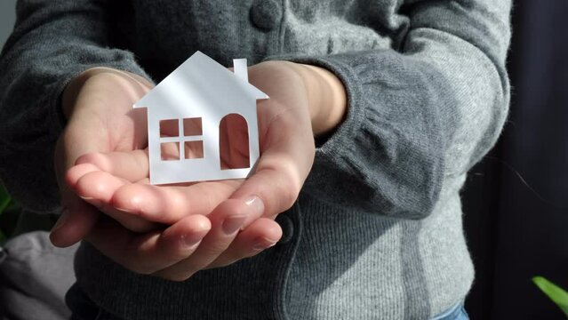Close up of female hands holding paper house, family home, homeless housing and home protecting insurance concept, international day of families, foster home care, homeschooling, social distancing