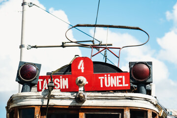 Taksim Tunnel signboard front of the famous red tram in Istanbul, close up to retro train, travel and sightseeing concept in Turkey, historical tram with blue cloudy sky