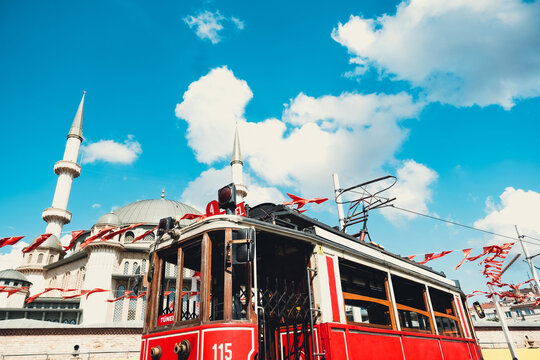 Taksim historical tram with Taksim Mosque in background, beautiful cityscape in Istanbul, blue cloudy sky, travel destination in Turkey, scenery retro train in sunny day, sightseeing place in Istanbul