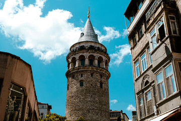 Fototapeta na wymiar Galata Tower between two buildings in Istanbul, old famous building in Turkey, beautiful landscape with historical architecture and blue sky, tourism and sightseeing idea, Istanbul travel destination