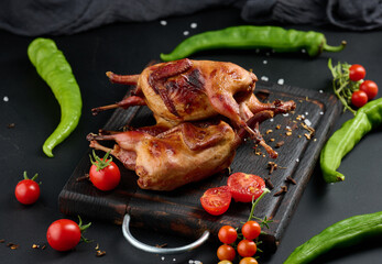 Frying carcasses of quails lie on a wooden board with vegetables