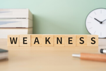 WEAKNESSと書かれた積み木が置かれたデスク
