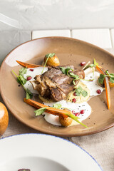 Roast Lamb leg with carrot, potato and pomegranate on brown plate on the table