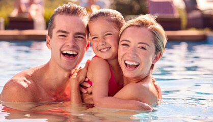 Portrait Of Smiling Family On Summer Holiday Relaxing In Swimming Pool