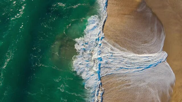 Cenital view of the sea and the waves on a spring day, blue, green and orange combinatios
