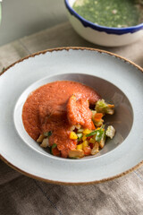 Tasty appetizing summer tomato soup puree gazpacho with vegetebles served in bowl on the table