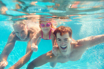 Portrait Of Multi-Generation Family On Summer Holiday Swimming Underwater In Pool