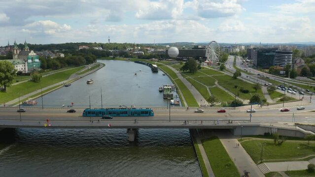 Aerial drone shot of flyover of Wisła Vistula River near the modern city center of Krakow, Poland with cars passing by over the bridge.