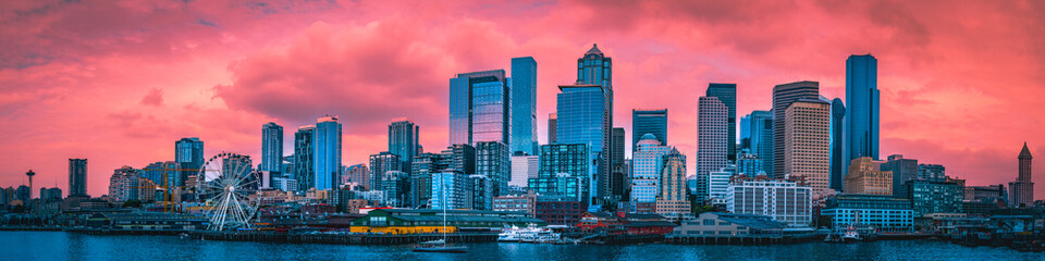 Seattle city skyline at sunset, dramatic pink cloudscape over the financial district buildings, and Elliot Bay in Washington State, USA