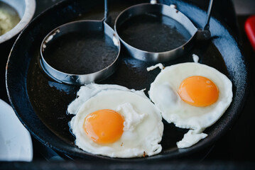 Fried eggs in a pan and a mold for frying eggs.