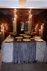 Golden plates, candles  and glasses for decorating of candy bar.
