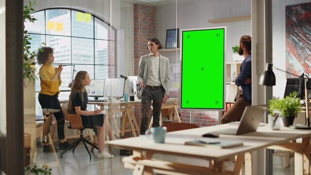 Young Businessman Leading a Team Meeting in Creative Office Conference Room. Confident Stylish Manager Showing Presentation on Green Screen Mock Up Chroma Key Monitor.