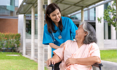 Obraz premium Asian careful caregiver or nurse taking care of the patient in a wheelchair. Concept of happy retirement with care from a caregiver and Savings and senior health insurance, a Happy family
