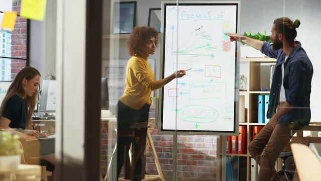 Positive Businesswoman Making a Team Presentation in a Meeting Room in Creative Office. Excited Arab Female Discussing a New Project Plan on Digital Whiteboard Display. Handheld Shot.