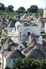  typical trulli houses in Alberobello, Puglia, Italy. Traditional symbols are painted on the conical roofs. A trullo is a traditional Apulian stone dwelling in Itria Valley.
