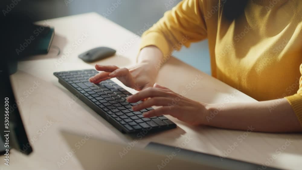 Aufkleber Stylish Female Employee in Bright Yellow Sweater Working Online on Computer in Office During a Sunny Day. Close Up on Hands of a Manager Typing Texts on a Keyboard, Writing Emails and Using Mouse.