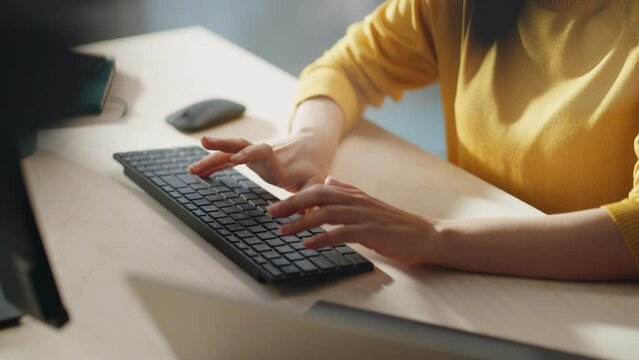Stylish Female Employee in Bright Yellow Sweater Working Online on Computer in Office During a Sunny Day. Close Up on Hands of a Manager Typing Texts on a Keyboard, Writing Emails and Using Mouse.