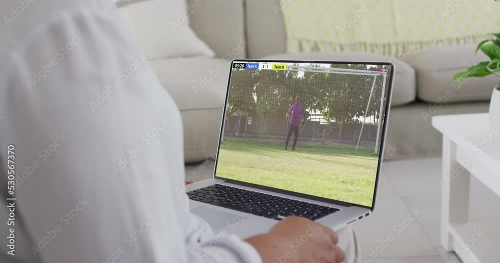 Sticker Hands using laptop with african american male soccer player playing match on screen