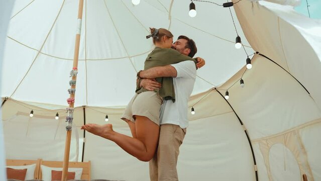 Cheerful blond young couple dancing and hugging in a tent