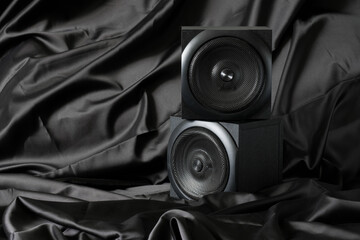 Two wooden multidirectional audio speakers are set in a natural silk interior. Concept of softening...