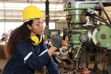 Technician engineer or worker woman in protective uniform with safety hardhat maintenance operation or checking lathe metal machine at heavy industry manufacturing factory. Metalworking concept