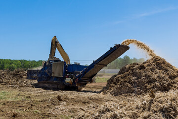 Fototapeta na wymiar Land on which is going be built has roots that are being shred into chips by an industrial shredder machine to land clearing property housing development