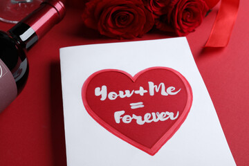 Card with romantic message, wine and roses on red background, closeup. Love confession