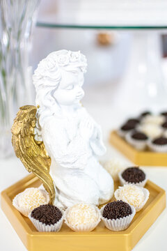 Anjinho decorativo para festa. Um anjo ajoelhado com docinhos de festa ao seu redor. Decora&ccedil;&atilde;o de Festa de Primeira Eucaristia. 