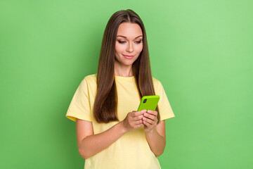 Photo of cute sweet positive good mood girl with straight hairdo dressed yellow t-shirt chatting writing message on green color background