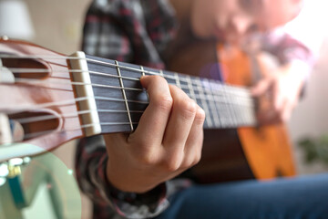 Fototapeta na wymiar Fingers of a child playing the guitar. Girl playing guitar at home.