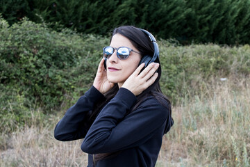 Women closeup outdoors with headphones and sunglasses