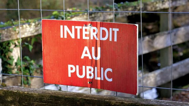 Sign indicating "forbidden to the public" in French on a fence of a wooden footbridge in a forest on an autumn day