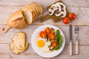 Breakfast on the table with fried eggs and spinach, tomatoes and mushrooms. Flat lay.