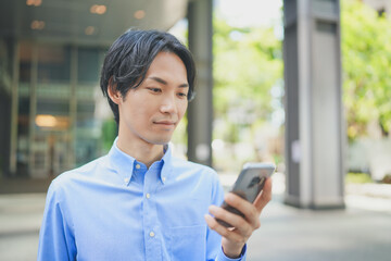 Fototapeta na wymiar オフィス街でスマートフォンを操作するビジネスマン