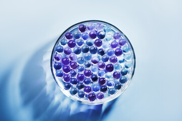 Sample of gel bubbles in petri dish on blue background, hard shadows. Abstract science, medicine...