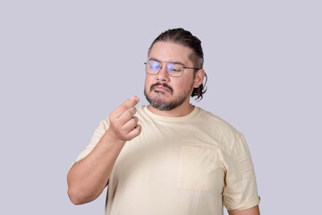 An man in his 30s inspects a booger picked form his nose. Isolated on a gray background.