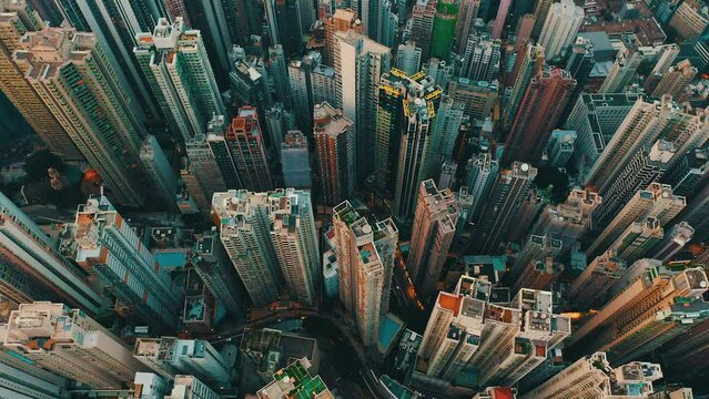Drone shot traveling forward and panning down toward a huge city with hundreds of skyscrapers during the day. It's an urban jungles like a maze and the streets busy with cars