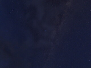 雲のかかる夜空に浮かぶ天の川と星の写真