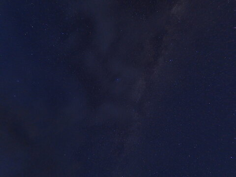 雲のかかる夜空に浮かぶ天の川と星の写真