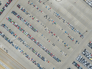 Top down aerial view of import and export car automobile storage in harbour port. Automotive industry new vehicles parked lot ready for shipping. Economy business export.