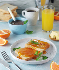 Sandwiches with marmalade, orange juice and coffee ready for breakfast	