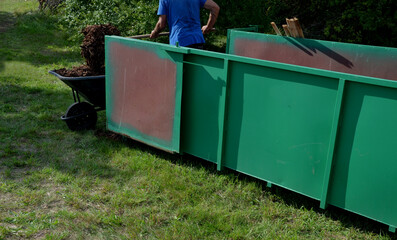 loading wood chips bark on a wheelbarrow  with a shovel from a car and delivery to the garden where...