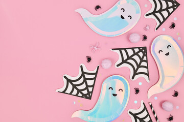 Cute pastel colored Halloween party flat lay with ghost shaped plates, spider web napkins and...