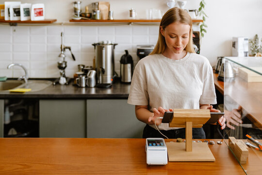 Blonde white barista woman working with tablet computer in cafe