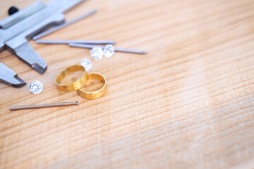 Fototapeta na wymiar Wedding golden rings and professional jeweler equipments. Luxury diamonds on wood background
