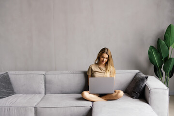 Cozy workplace. Relaxed freelancer girl working with laptop at home