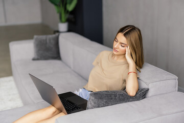 Young Woman using a laptop while relaxing on the couch